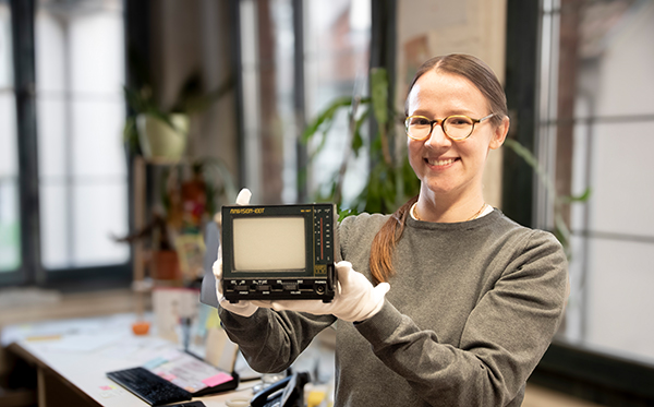 Auf dem Bild ist eine Frau zusehen, die Tübinger Historikerin Marina Chernykh. Sie hält einen alten kleinen Fernsehapparat in den Händen, mit dem die Italienerin Antonie Pricci früher Deutsch gelernt hat.