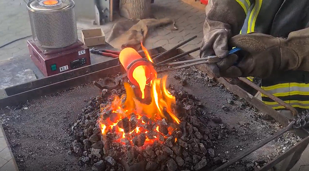 Metall wird über einem glühenden Feuer zum Schmelzen gebracht.