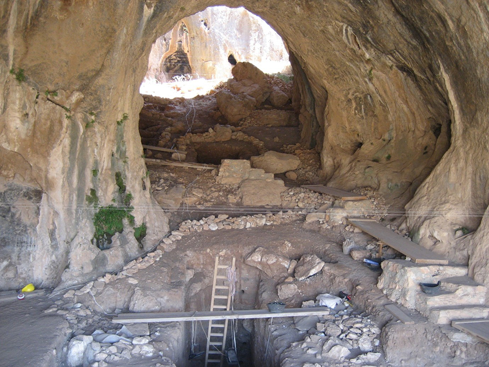 Ein großer Hohlenraum mit Ausgrabungen, Mauern, Treppen und einer Leiter.