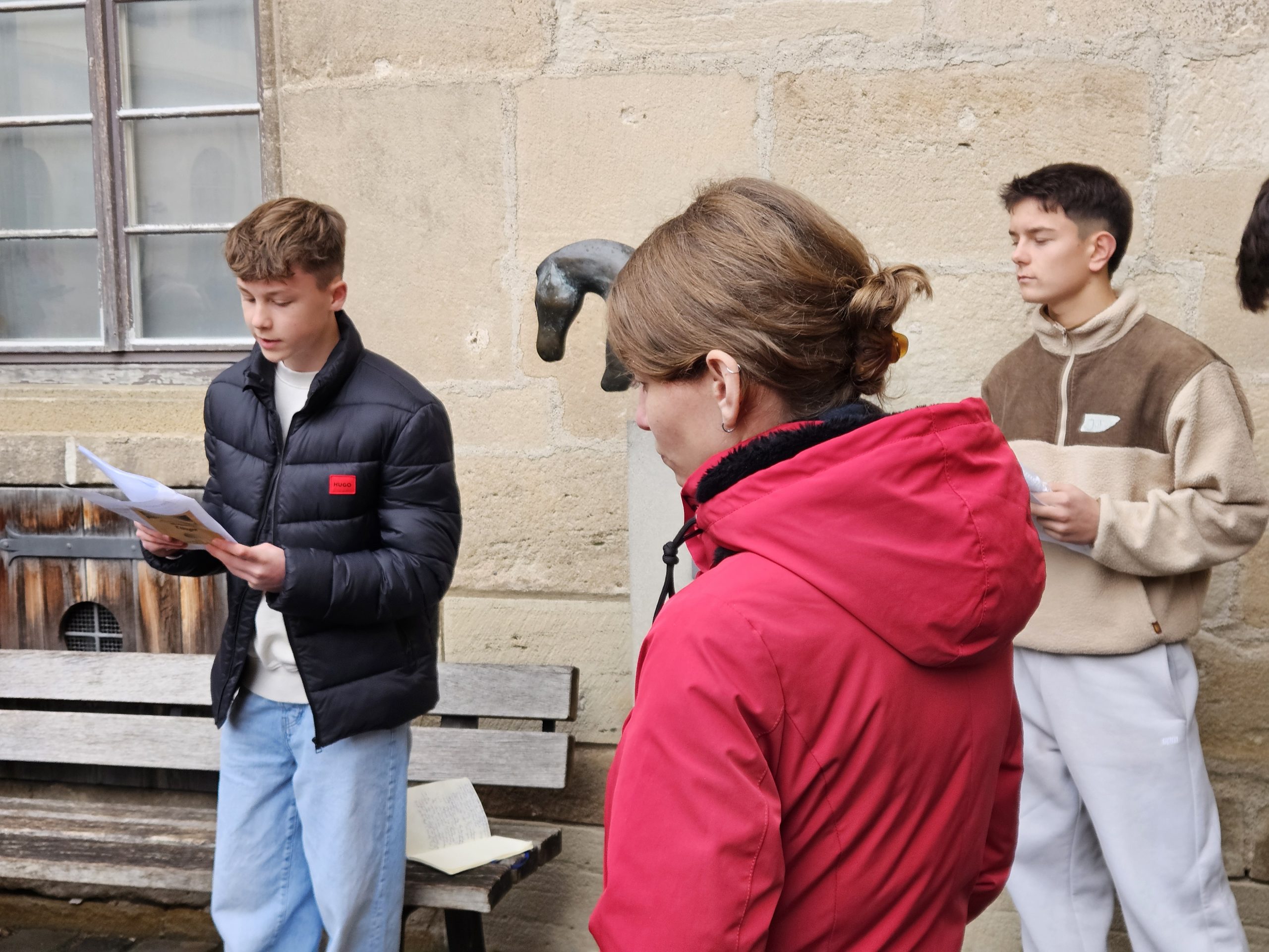 Im Innenhof des Tübinger Schlosses, vor einem vergrößerten Abguss des Urzeitpferdes. Eine junge Frau und zwei junge Männer mit Fotokopien in der Hand.