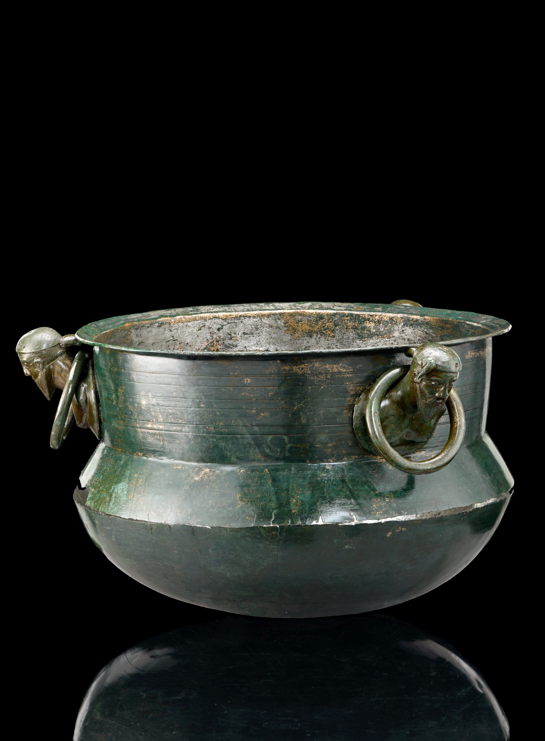 Das Foto zeigt einen Kessel, an dem drei Köpfe gestaltet sind.