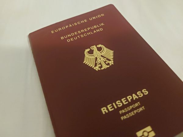 Auf dem Tisch liegt ein dunkelroter Reisepass der Bundesrepublik Deutschland.