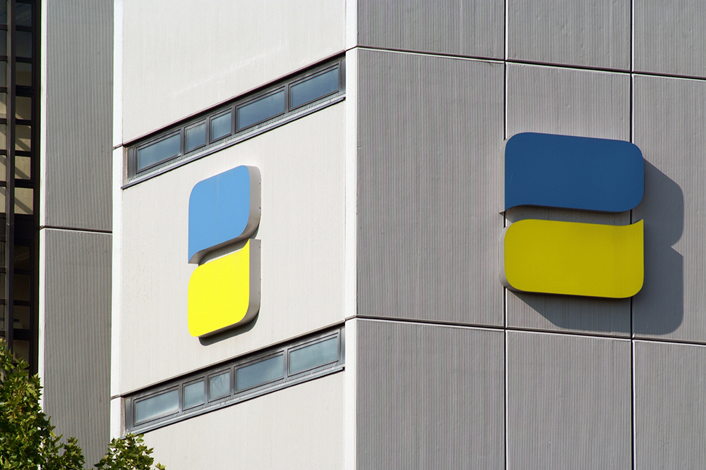 Das zweifarbige Logo der Deutschen Rentenversicherung (DRV) auf einer Betonfassade.